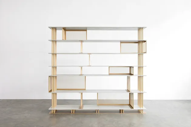 Brass-framed shelving unit in a white gallery