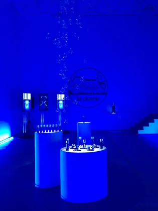 La Prairie event: lit product plinths, screens and hanging glass under deep blue light